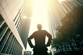 Man in a suit looking up at tall buildings