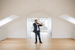 Man taking a photo of empty finished attic space with cell phone