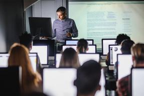 Man teaching a class of students at computers