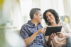 Middle-aged couple sitting on a couch with a tablet