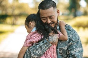 Military father hugging young daughter