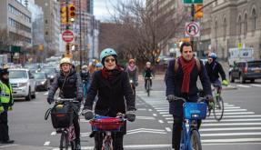 People in bicycles crossing a busy urban intersection in New York City
