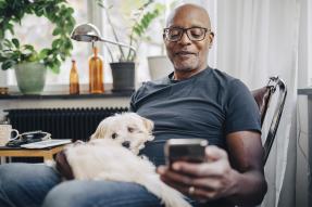 Older man holding a dog and checking his cell phone