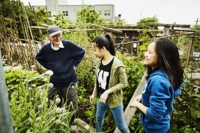 Older man with two young women in community garden