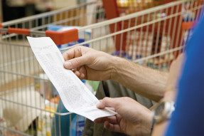 People holding a receipt with shopping cart in the background