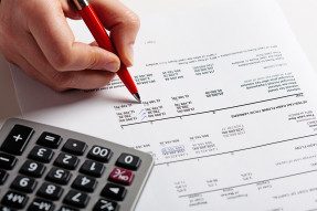 Person reviewing a financial report with pen and calculator
