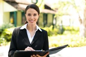 Professional woman with portfolio standing outside a house