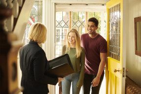 Real estate agent welcoming young couple into a home