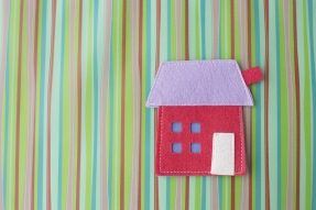 Red felt house on striped background