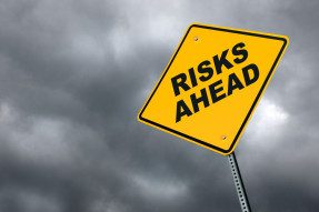Risks ahead road sign in front of cloudy sky background
