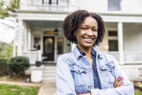Portrait of single African American woman in front of beautiful suburban home
