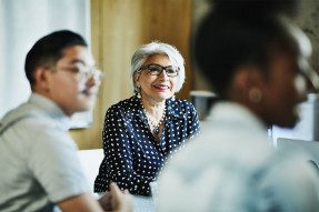 Smiling white-haired Latinx woman in a meeting