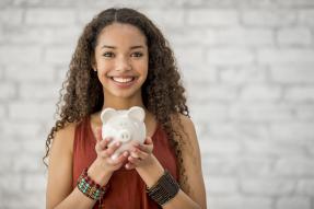 Smiling young woman holding a piggy bank