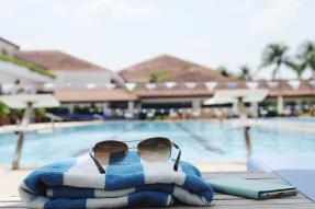 Sunglasses, towel, and phone next to a pool at a resort