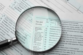 Tax forms with magnifying glass on tax and credits section