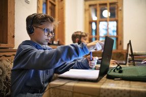 Two children attending remote school via laptops