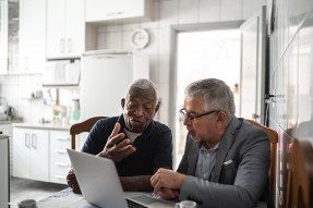 Two men at a laptop in a kitchen