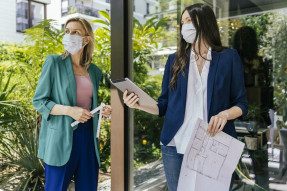Two women wearing face masks while inspection outdoor area of house