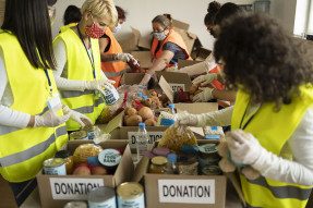 Volunteers wearing masks packing boxes of food