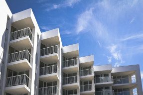 White apartment building with balconies and  blue sky background