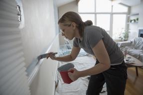 Woman painting a wall above a chair rail