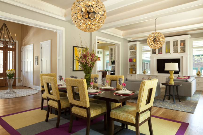 Bright dining room that includes dark wood table and yellow upholstered chairs under a modern chandelier