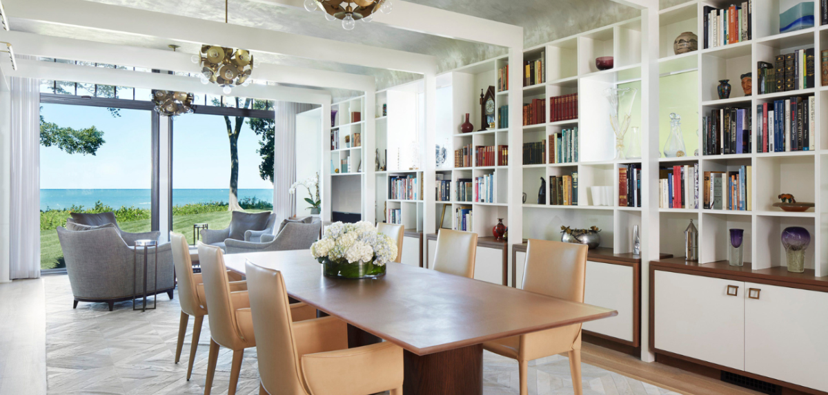 Photo of a bright living room and dining room with built in bookshelves