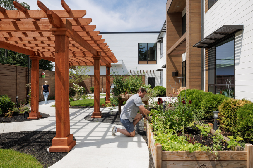 man tending to a raised garden bed outside a multifamily community