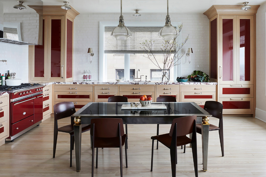 Modern kitchen with light cabinetry and deep red accents, table instead of island in the center