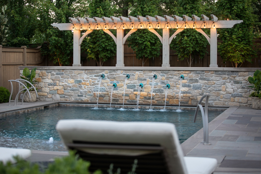 Pool with stone wall that includes a water feature of individual streams pouring back into the pool from the wall
