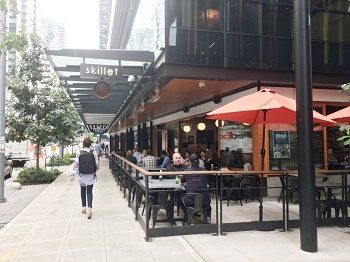 A corner restaurant with outdoor sitting next to a sidewalk