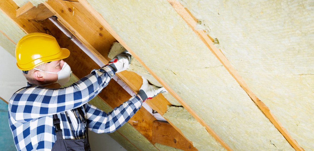 Worker installing insulation in attic