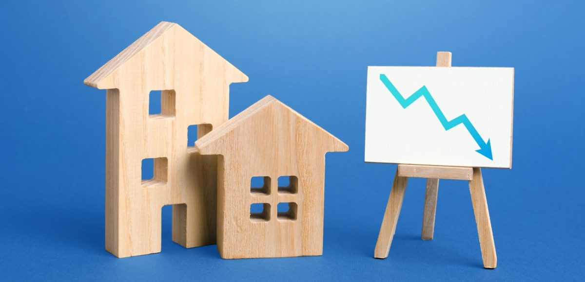 Wooden house figurines with chart and downward arrow