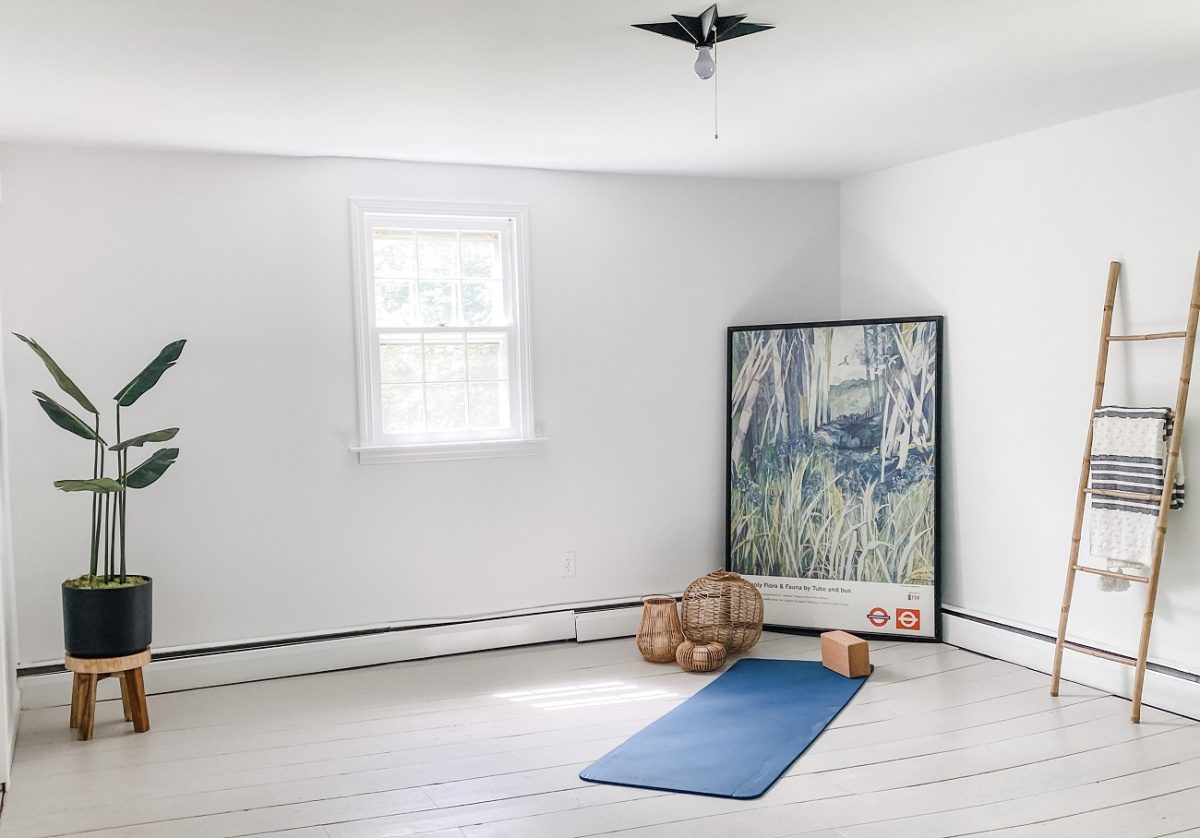 A previously cluttered room is transformed by white walls and minimal furnishings to accommodate a yoga room