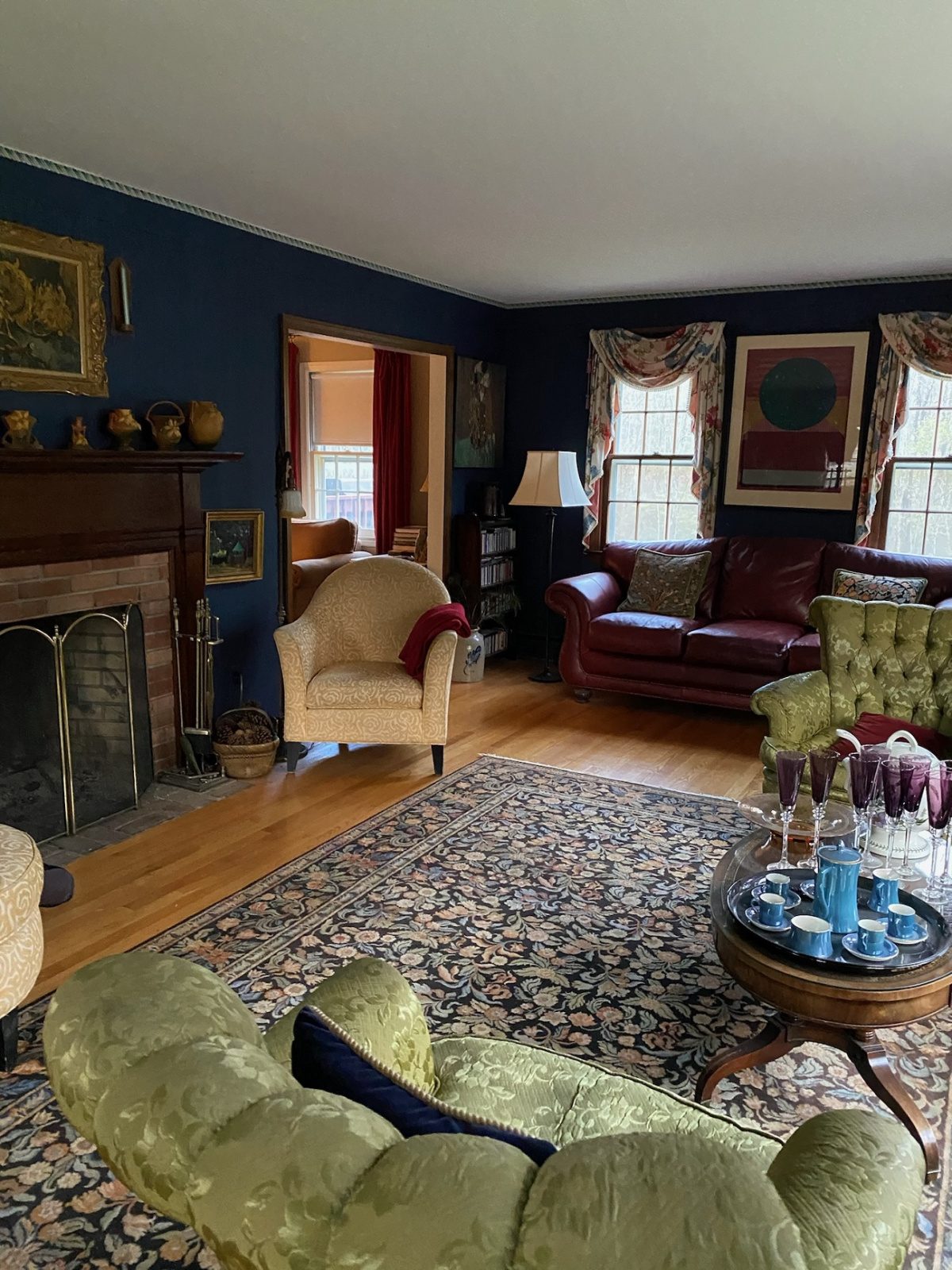 A living room space with dark blue walls and dark furnishings before being redesigned and staged