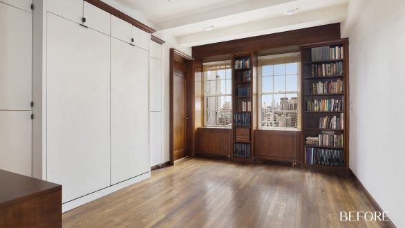 An empty room with windows and brown built-in bookshelves flanking the windows