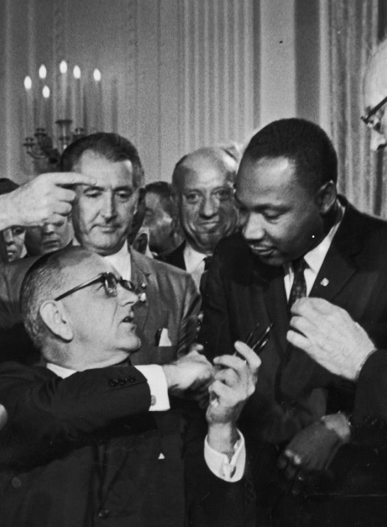 US President Lyndon B. Johnson shakes the hand of Dr. Martin Luther King Jr. at the signing of the Civil Rights Act