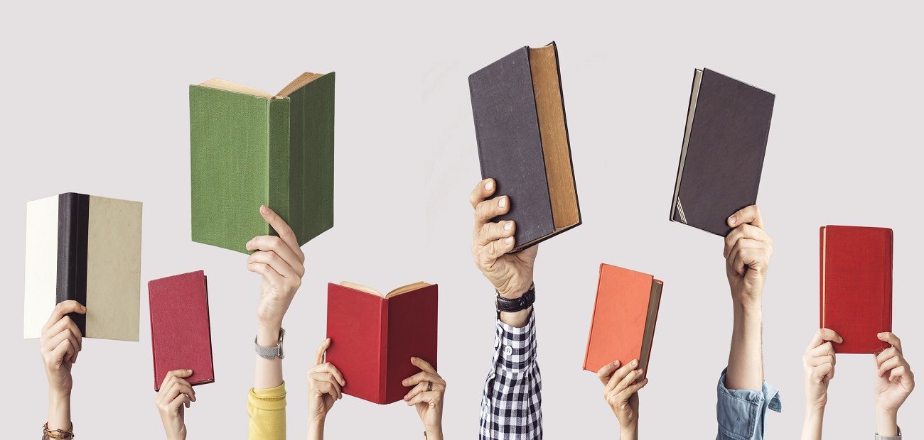 a bunch of hands holding up different colored books