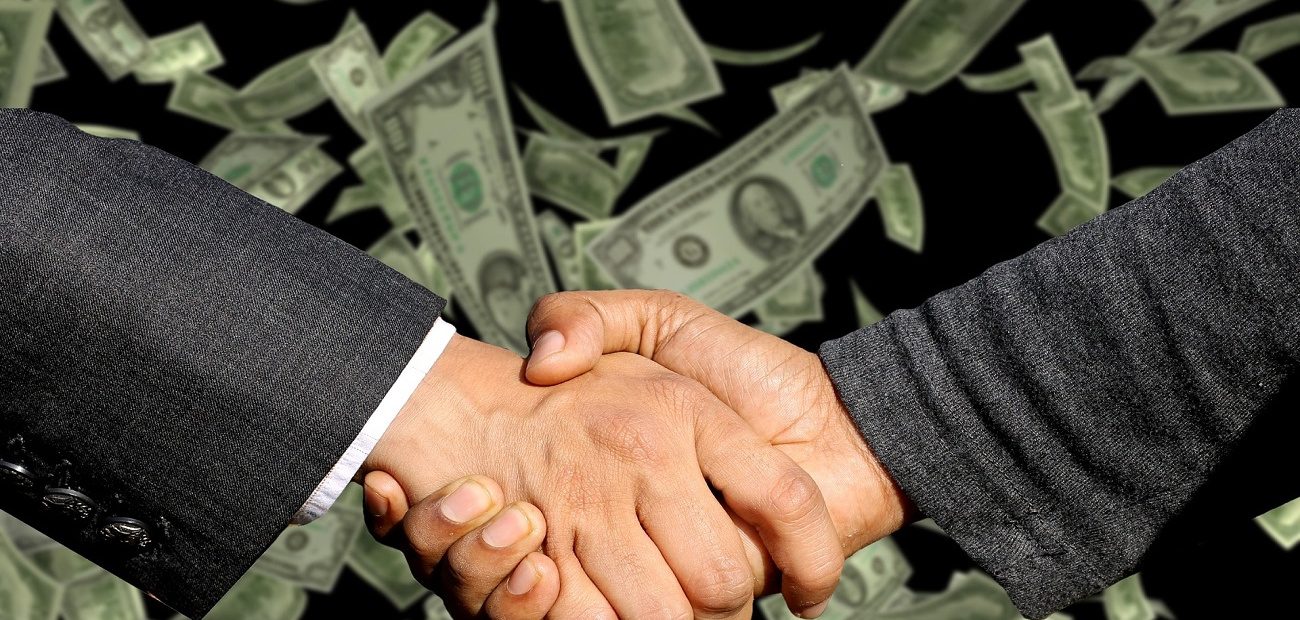 businessmen shaking hands with money in the background