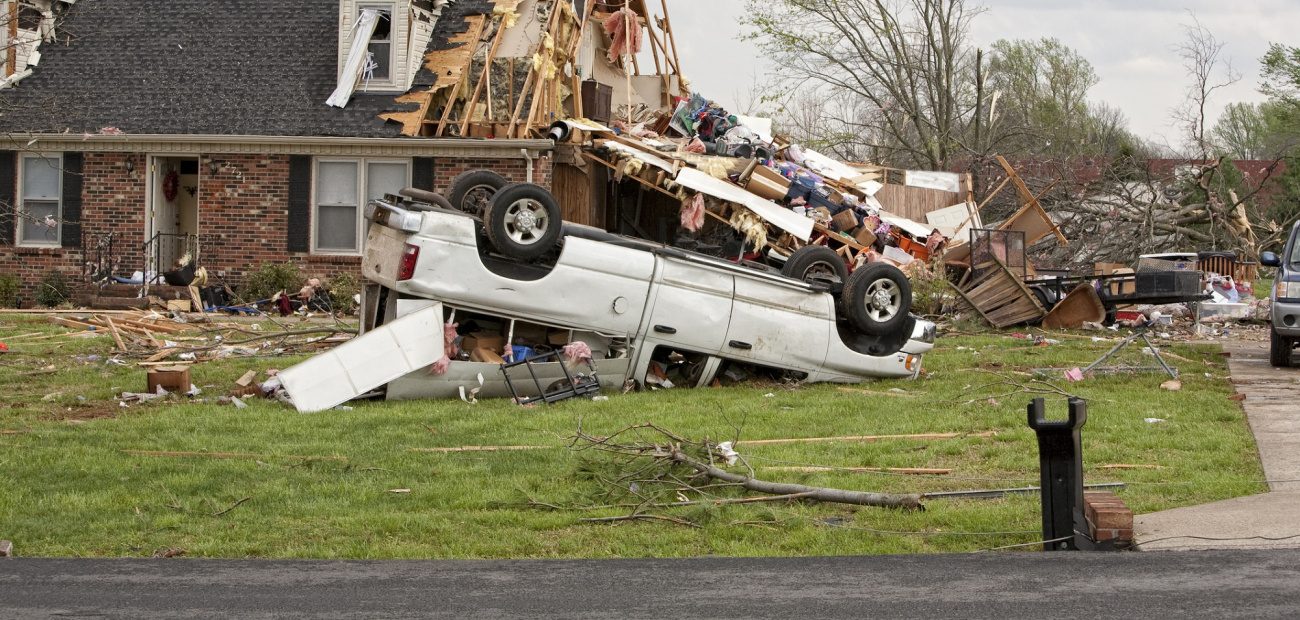A house destroyed by a tornado featuring a pick-up truck upside down in its front yard