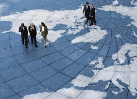 Business professionals walking across a world map floor