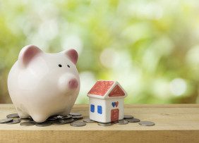 Ceramic piggy bank and house on a shelf with coins