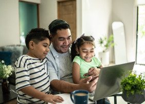 Father and two children at laptop in living room