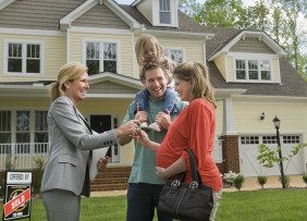 Female REALTOR® delivering keys to young family