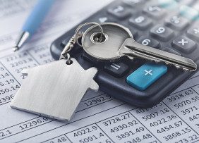 Financial papers, calculator, key on house keychain