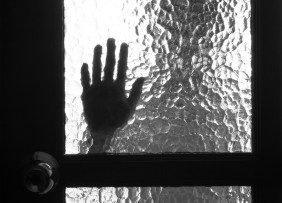 Silhouette of person and hand on window