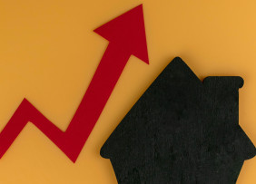 llustration: Rising red line graph arrow next to black house shape on yellow background