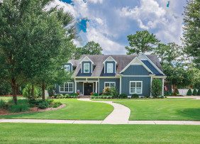 Large blue Craftsman house with large front lawn and trees