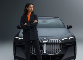 Woman wearing a suit and standing in front of a Mercedes Benz
