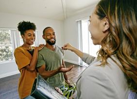 Real estate agent handing clients a key in an empty house